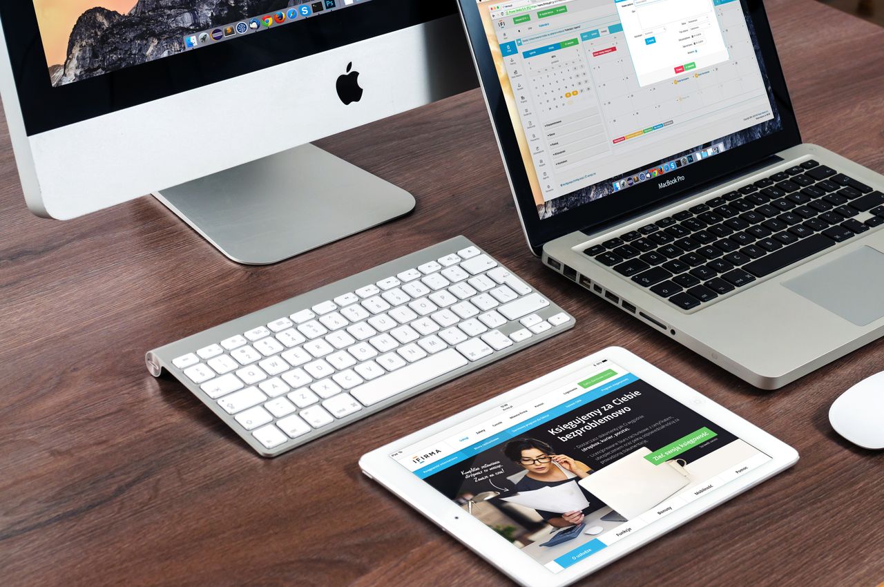 A stylish office desk arrangement showcasing Apple devices: iMac, MacBook, and iPad.
