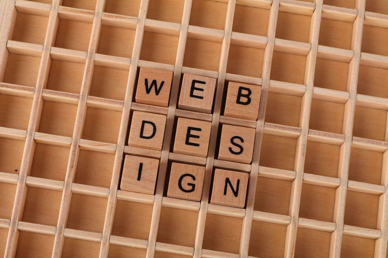 Wooden blocks arranged to spell web design on a grid backdrop, representing imaginative digital design ideas.